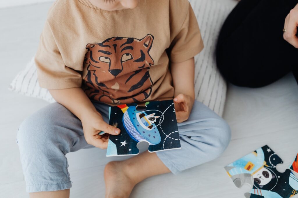 Enfant tenant une pièce de puzzle spatial, outil pour enfants TSA
